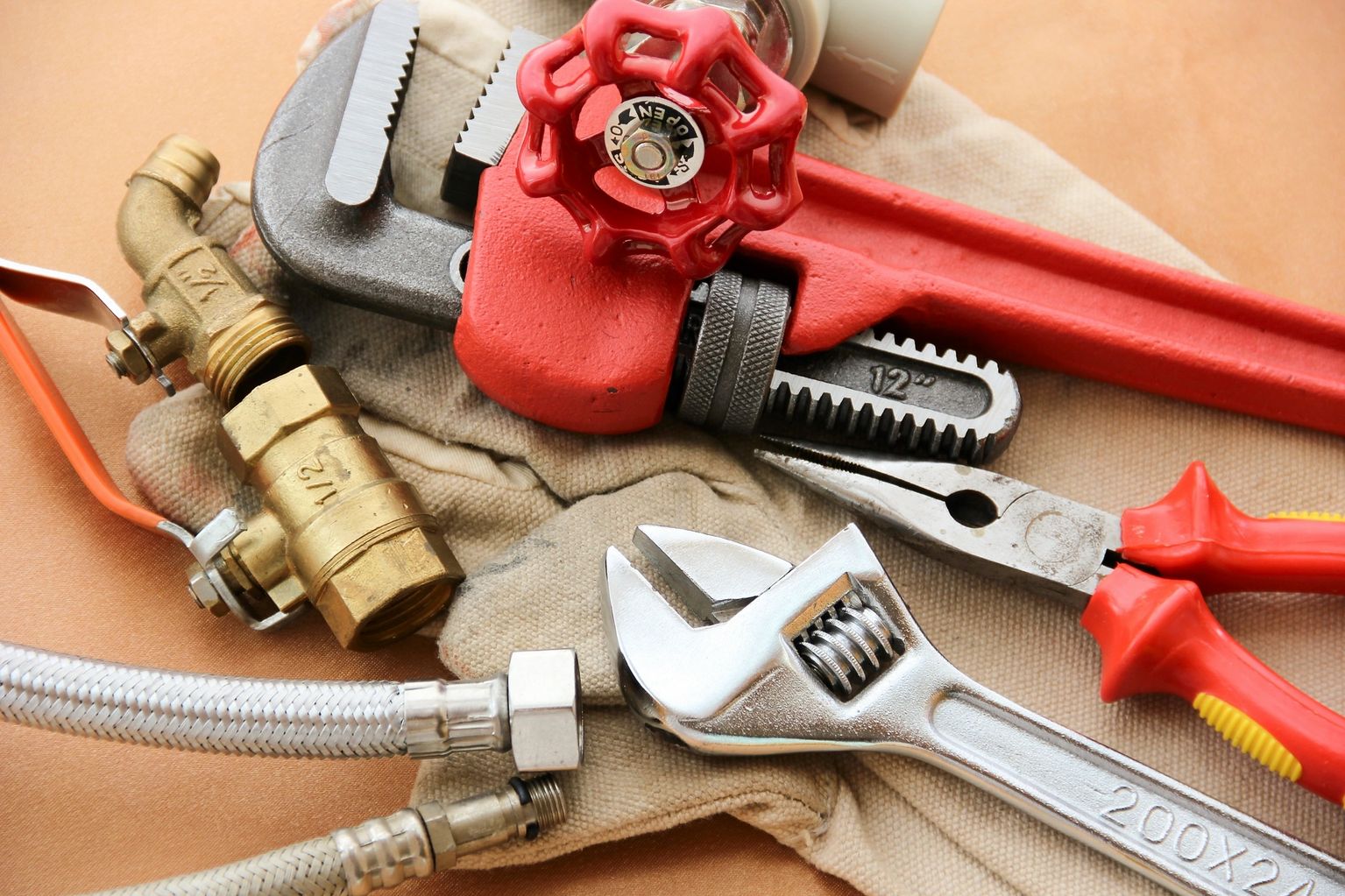 Pipe wrenches, an adjustable wrench and brass valve fittings laid out on canvas